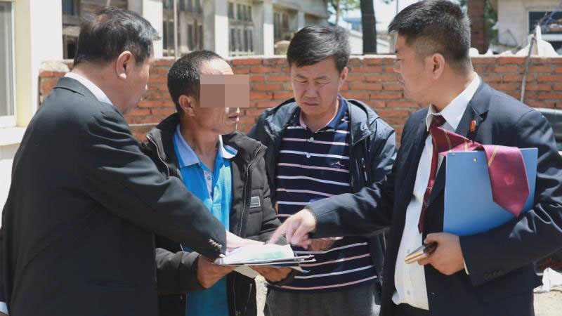 擋臉！第二稿配圖：執行法官及工作人員為被執行人解釋生效文書內容并督促其騰房