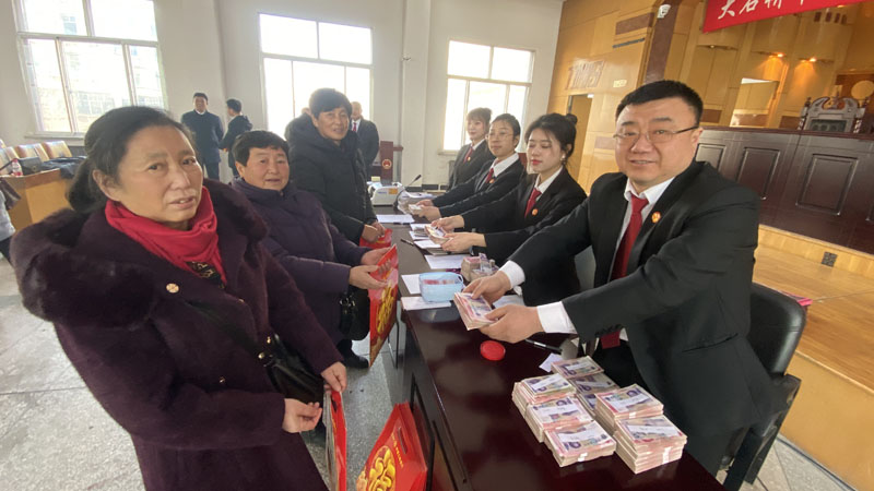 徐斌（左二）領取工資款；右一是大石橋市人民法院執行員王敬偉
