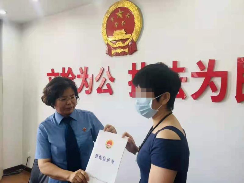 監護人（右）從檢察官手中接過《督促監護令》