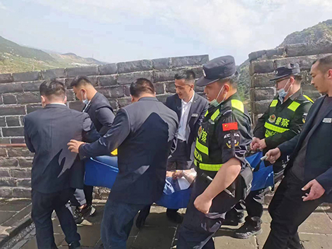 民警與景區(qū)工作人員將患病游客抬下長(zhǎng)城。