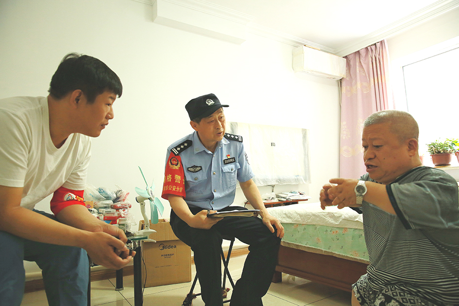 臨退休前，社區(qū)民警王忠利（左二）和網(wǎng)格員去劉學成家中走訪