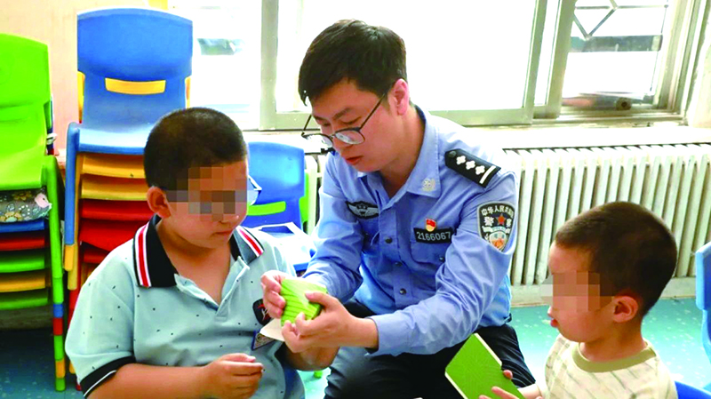 二題圖，民警在營口市金石自閉癥兒童幼兒園指導孩子制作粽子折紙